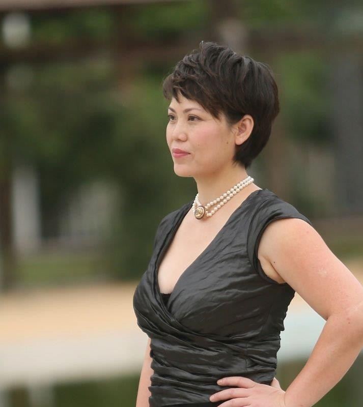 Sophia outdoors in a dark dress and pearl necklace